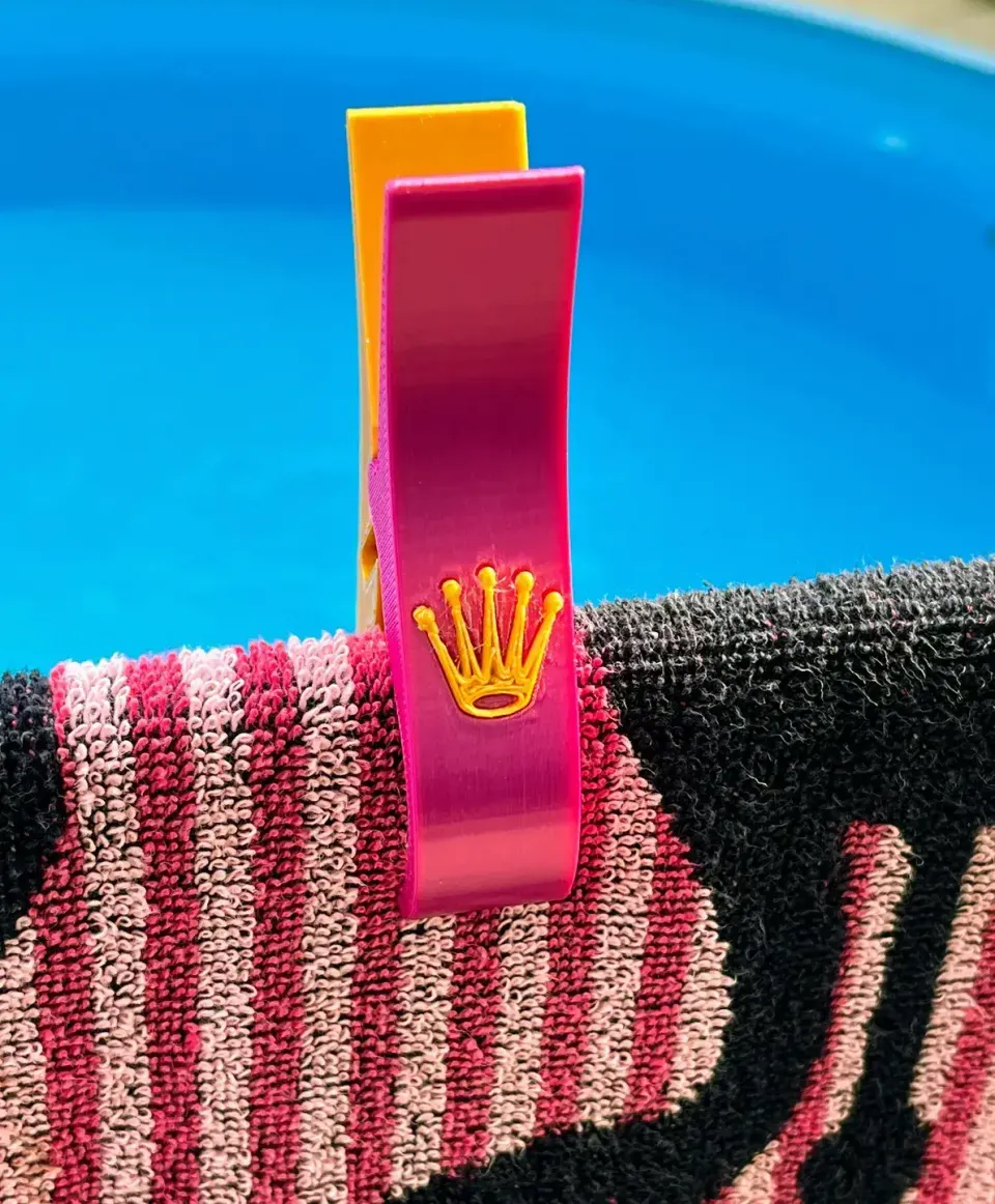 Barevný 3D tištěný klip drží plážovou osušku u bazénu