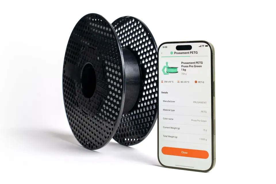 Filamentová cívka vedle telefonu s aplikací OpenPrintTag zobrazující údaje o materiálu a hmotnosti