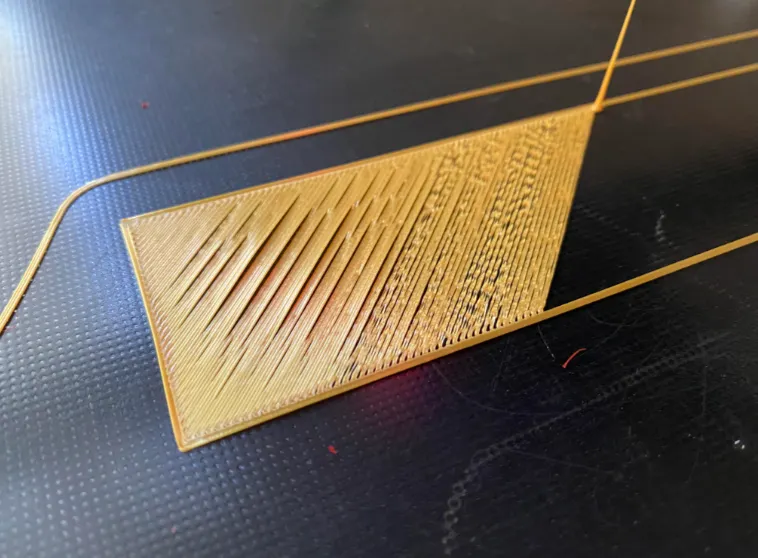 Detail výtisku s hrubým povrchem, nepravidelnou extruzí a mezerami typickými pro problémy s navlhlým filamentem.