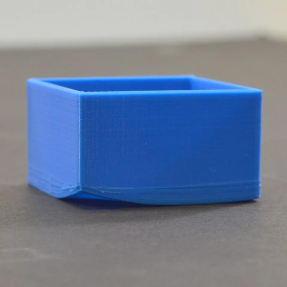 Modrý 3D výtisk se zvednutým rohem kvůli kroucení materiálu při tisku