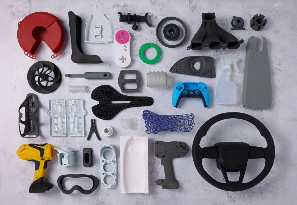 Různé 3D tištěné díly a prototypy ukazující odlišné nároky na materiál, pevnost a povrchovou úpravu.